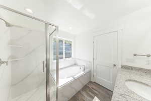 Full bath featuring wood finished floors, a marble finish shower, a garden tub, vanity, and recessed lighting