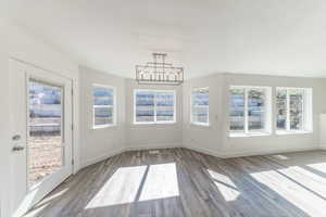 Dining area featuring healthy amount of natural light, wood finished floors, a chandelier, and a textured ceiling