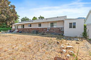 Rear view of property with brick siding, entry steps, a patio, and solar panels