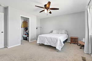 Carpeted bedroom featuring a ceiling fan and a walk in closet