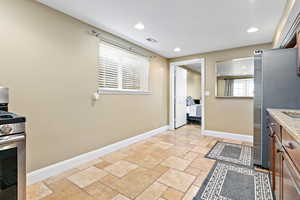 Kitchen with stainless steel appliances, stone tile flooring, and recessed lighting