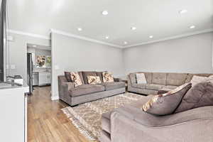 Living room featuring recessed lighting, crown molding, and light wood-type flooring