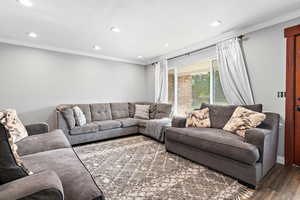 Living room with ornamental molding, dark wood-type flooring, and recessed lighting