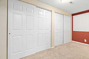Unfurnished bedroom with carpet floors and two closets
