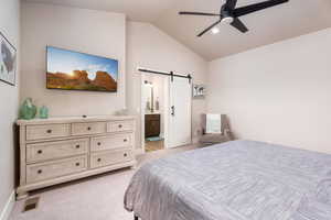 Bedroom with a barn door, light carpet, recessed lighting, connected bathroom, and ceiling fan