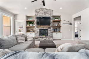 Living room featuring light colored carpet, a ceiling fan, a stone fireplace, and recessed lighting
