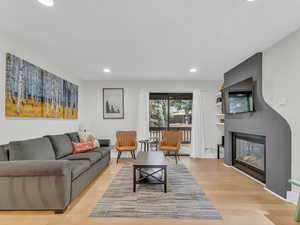 Living area featuring recessed lighting, light wood-style floors, and a glass covered fireplace