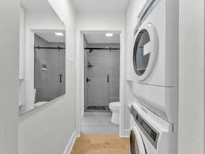 Bathroom featuring stacked washing machine and dryer and a shower stall