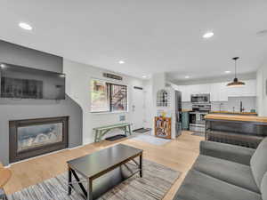 Living area featuring a glass covered fireplace, recessed lighting, and light wood-style floors