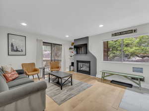 Living room with a glass covered fireplace, light wood-style floors, and recessed lighting