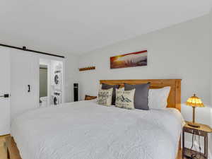 Bedroom with stacked washer / drying machine, a barn door, and ensuite bath