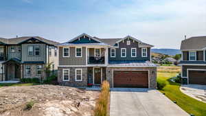 Craftsman house with stone siding, a standing seam roof, and an attached garage