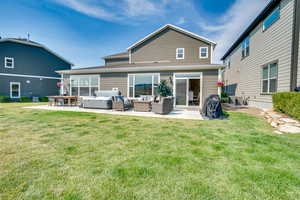 Back of property with an outdoor hangout area, a patio, roof with shingles, and a yard