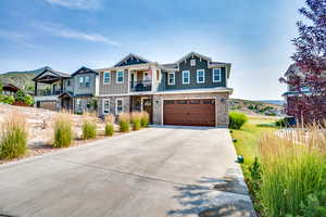 Craftsman house featuring a garage, a balcony, stone siding, driveway, and a mountain view