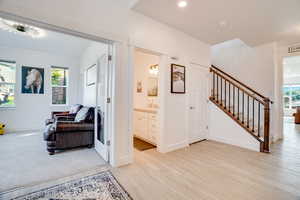 Hallway featuring plenty of natural light, stairs, and light wood-type flooring