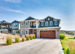 Craftsman house featuring an attached garage, a balcony, concrete driveway, and stone siding