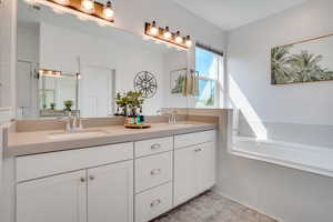 Full bathroom featuring double vanity and tiled bath