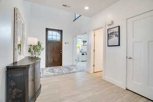 Foyer entrance with light wood finished floors and recessed lighting