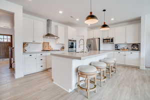 Kitchen featuring white cabinetry, a center island with sink, light countertops, and recessed lighting