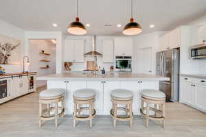 Kitchen with light countertops, backsplash, appliances with stainless steel finishes, a breakfast bar, and recessed lighting