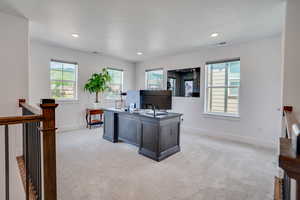 Home office featuring light colored carpet, plenty of natural light, a textured ceiling, and recessed lighting