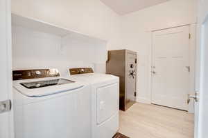 Laundry room featuring independent washer and dryer and light wood finished floors