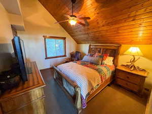 Bedroom featuring lofted ceiling, wooden ceiling, carpet flooring, and ceiling fan