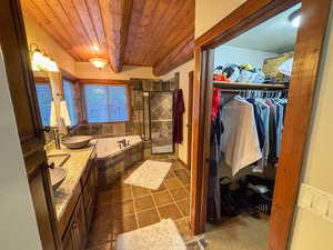 Full bath with a wooden ceiling with exposed beams, a garden tub, double vanity, a spacious closet, and tiled shower