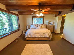 Bedroom with a wood ceiling with exposed beams, carpet flooring, and a ceiling fan