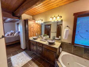 Ensuite bathroom with wooden ceiling, double vanity, a whirlpool tub, and tile patterned flooring