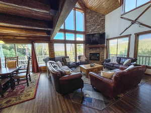 Living room with wood finished floors, wooden ceiling, high vaulted ceiling, and a fireplace
