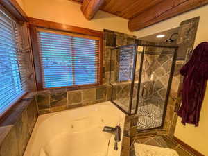 Full bath with a stall shower, a jetted tub, healthy amount of natural light, and a wood ceiling with exposed beams
