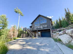 View of front of home with stairway, concrete driveway, stone siding, and a garage
