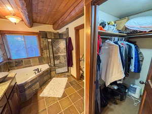 Full bathroom with a wooden ceiling with exposed beams, a jetted tub, tiled shower, and vanity