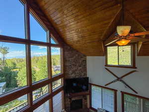 Living room with wood ceiling, a stone fireplace, and high vaulted ceiling