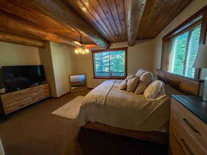 Carpeted bedroom featuring a wood ceiling with exposed beams and ceiling fan