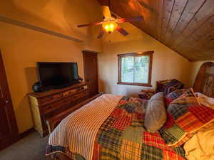 Bedroom with vaulted ceiling, wood ceiling, carpet flooring, and a ceiling fan