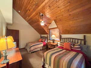 Carpeted bedroom featuring wood ceiling and lofted ceiling