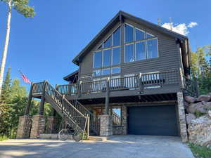 View of front of property with stairs, a garage, concrete driveway, and a wooden deck