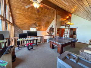 Recreation room featuring wood ceiling, high vaulted ceiling, carpet, and a ceiling fan