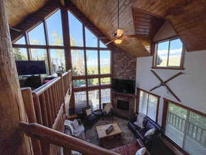 Living room featuring high vaulted ceiling, wooden ceiling, ceiling fan, and a fireplace