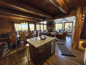 Kitchen with dark wood finished floors, a stone fireplace, a kitchen island, dark brown cabinetry, and a wood ceiling with exposed beams