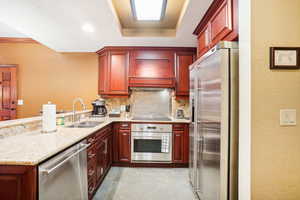 Kitchen featuring a textured wall, dark brown cabinets, stainless steel appliances, a peninsula, and tasteful backsplash