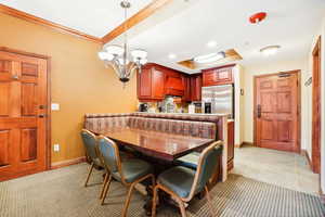 Dining space featuring a tray ceiling, a chandelier, ornamental molding, recessed lighting, and light tile patterned floors