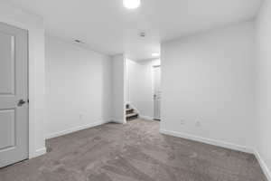 Carpeted spare room with stairs and baseboards