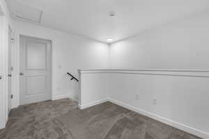 Empty room featuring carpet floors and attic access