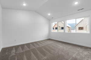 Empty room with lofted ceiling, dark colored carpet, and recessed lighting