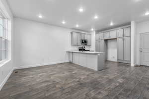 Kitchen featuring a peninsula, light countertops, gray cabinetry, dark wood finished floors, and recessed lighting