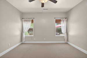 Carpeted empty room with baseboards and a ceiling fan