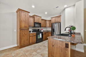 Kitchen featuring a peninsula, black appliances, brown cabinetry, a breakfast bar area, and recessed lighting
